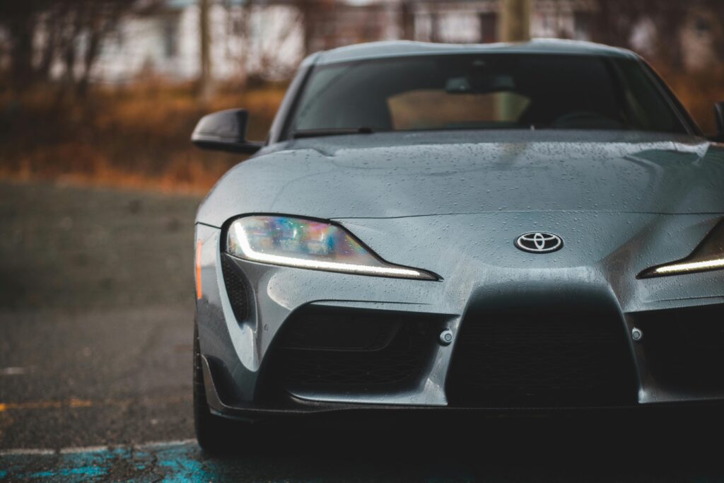 pexels-photo-4061413-4061413 Front view of a Toyota coupe with raindrops on windshield, parked outdoors.