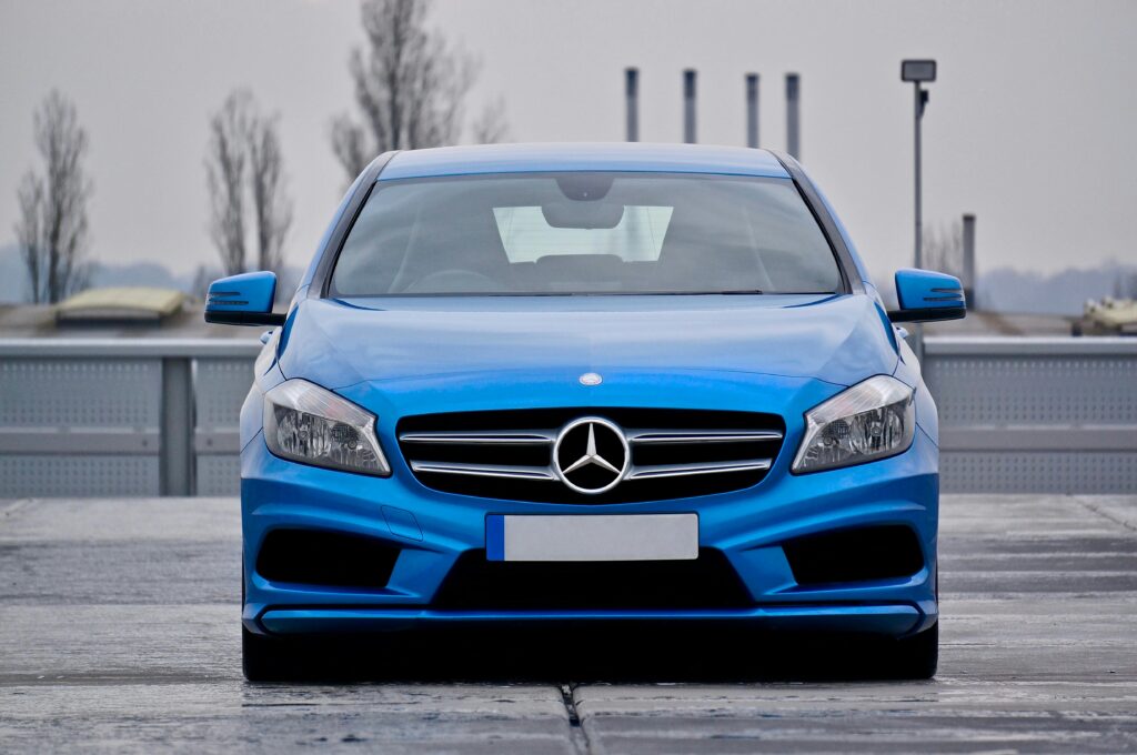 pexels-photo-802254-802254 Front view of a blue Mercedes-Benz car parked on a wet street under cloudy skies.